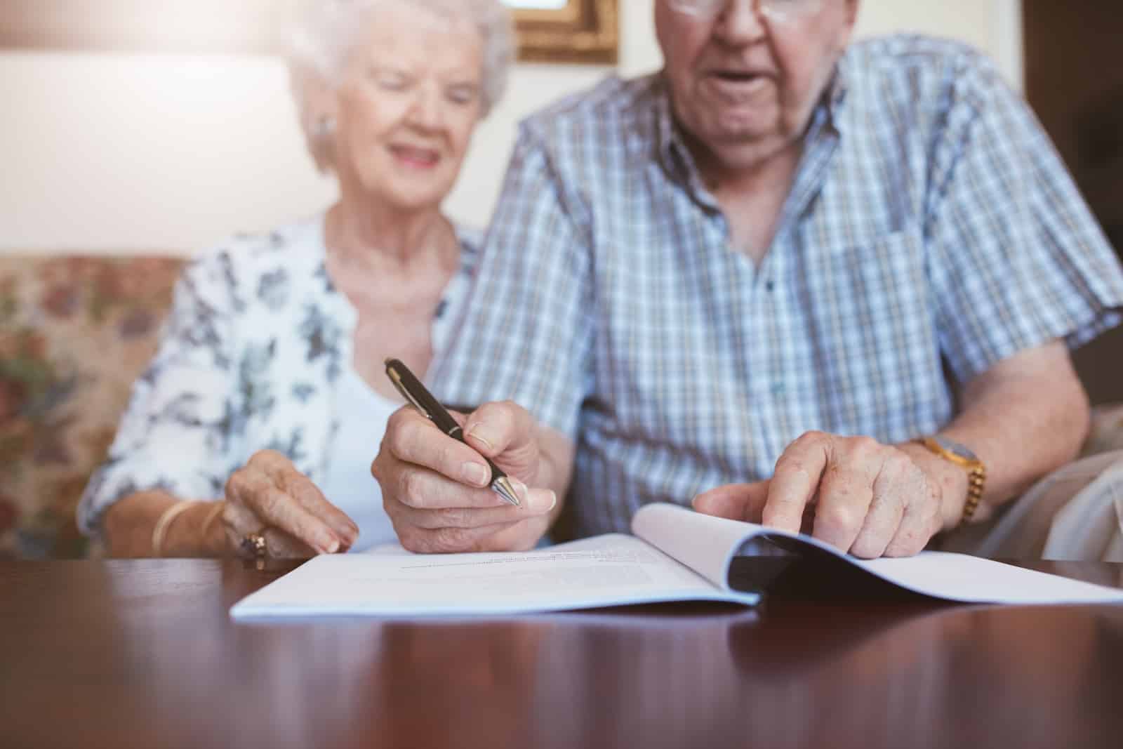 two elderly people signing a contract - advance medical directives